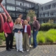 Eine Gruppe von fünf Menschen steht vor einem modernen Hochschulgebäude.